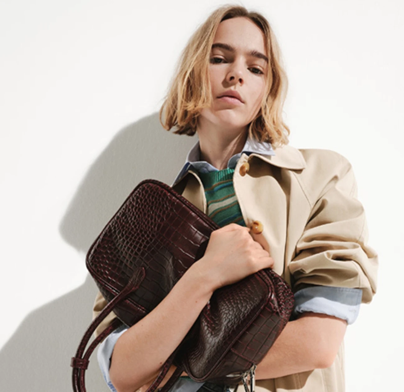 A model holding a burgundy leather in a croc pattern from the fashion label Mango which currently is on sale of up to 50% off on seasonal items