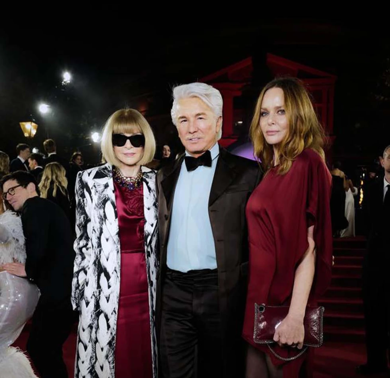 Anna Wintour wears a red velvet dress and a white printed padded coat