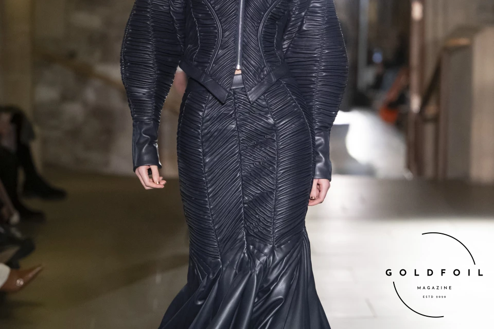 The  third most prominent look of the Mithridate AW24 collection included a full leather set in deep blue of a bar zip-up jacket with beautifully draped leather strips, accompanied by a skirt with the same stitching technique at the top, which from the knee spreads out and creates a more accentuated shape The  third most prominent look of the Mithridate AW24 collection included a full leather set in deep blue of a bar zip-up jacket with beautifully draped leather strips, accompanied by a skirt with the same stitching technique at the top, which from the knee spreads out and creates a more accentuated shape