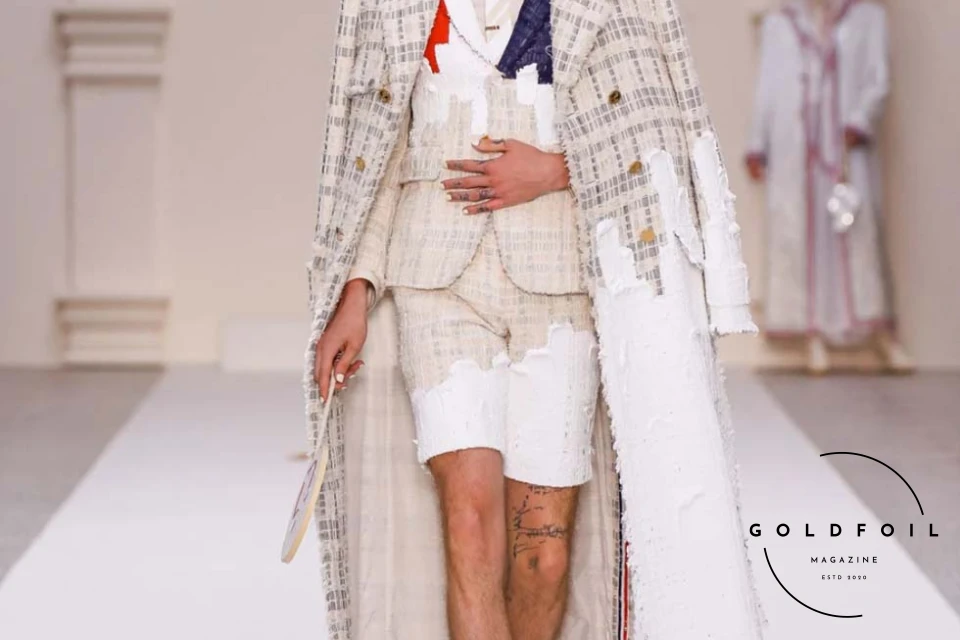 Thom Browne drew inspiration from the upcoming Olympic Games and sports throughout the centuries for his latest collection. The opening was nothing short of a spectacle, with the games beginning beneath the glow of five luminescent spheres. Spectators arrived in custom muslin smocks given prior to the show by the designer, each tagged with their names in classic Thom Browne calligraphy. At the centre of the hall, sixteen athletes in summer-weight cotton tailoring competed in a tug-of-war, their bodies in tension, showcasing strength in a back-and-forth struggle that eventually brought forth a winner. Thom Browne drew inspiration from the upcoming Olympic Games and sports throughout the centuries for his latest collection. The opening was nothing short of a spectacle, with the games beginning beneath the glow of five luminescent spheres. Spectators arrived in custom muslin smocks given prior to the show by the designer, each tagged with their names in classic Thom Browne calligraphy. At the centre of the hall, sixteen athletes in summer-weight cotton tailoring competed in a tug-of-war, their bodies in tension, showcasing strength in a back-and-forth struggle that eventually brought forth a winner.