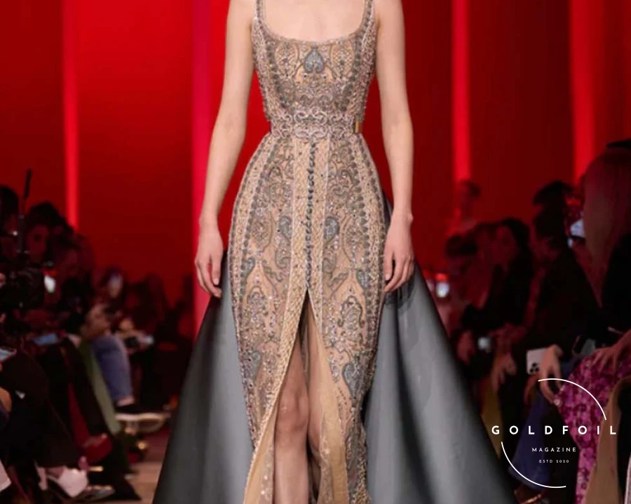 The show progressed from pitch-black to deep ruby and emerald tones, presenting sleek, sinuous shapes with sparse embroidery and tone-on-tone feathers and flower appliqués. As if emerging from darkness, gowns shimmered with moonlight-silver sequins, growing more sumptuous and voluminous. Rich embroidery and crystal beading adorned sensual see-through chiffon and organza, culminating in a lavish finale. The bridal dress was a cloud-like creation in blush tulle, intricately embroidered with pale gold curlicues and a regal train fit for a royal wedding. The show progressed from pitch-black to deep ruby and emerald tones, presenting sleek, sinuous shapes with sparse embroidery and tone-on-tone feathers and flower appliqués. As if emerging from darkness, gowns shimmered with moonlight-silver sequins, growing more sumptuous and voluminous. Rich embroidery and crystal beading adorned sensual see-through chiffon and organza, culminating in a lavish finale. The bridal dress was a cloud-like creation in blush tulle, intricately embroidered with pale gold curlicues and a regal train fit for a royal wedding.