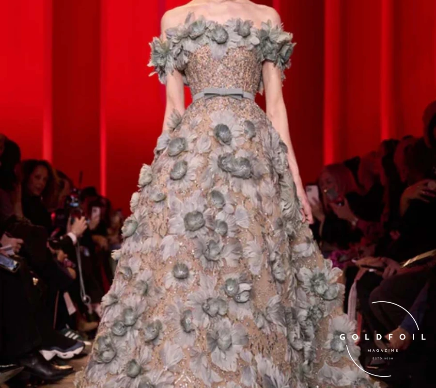 The show progressed from pitch-black to deep ruby and emerald tones, presenting sleek, sinuous shapes with sparse embroidery and tone-on-tone feathers and flower appliqués. As if emerging from darkness, gowns shimmered with moonlight-silver sequins, growing more sumptuous and voluminous. Rich embroidery and crystal beading adorned sensual see-through chiffon and organza, culminating in a lavish finale. The bridal dress was a cloud-like creation in blush tulle, intricately embroidered with pale gold curlicues and a regal train fit for a royal wedding. The show progressed from pitch-black to deep ruby and emerald tones, presenting sleek, sinuous shapes with sparse embroidery and tone-on-tone feathers and flower appliqués. As if emerging from darkness, gowns shimmered with moonlight-silver sequins, growing more sumptuous and voluminous. Rich embroidery and crystal beading adorned sensual see-through chiffon and organza, culminating in a lavish finale. The bridal dress was a cloud-like creation in blush tulle, intricately embroidered with pale gold curlicues and a regal train fit for a royal wedding.
