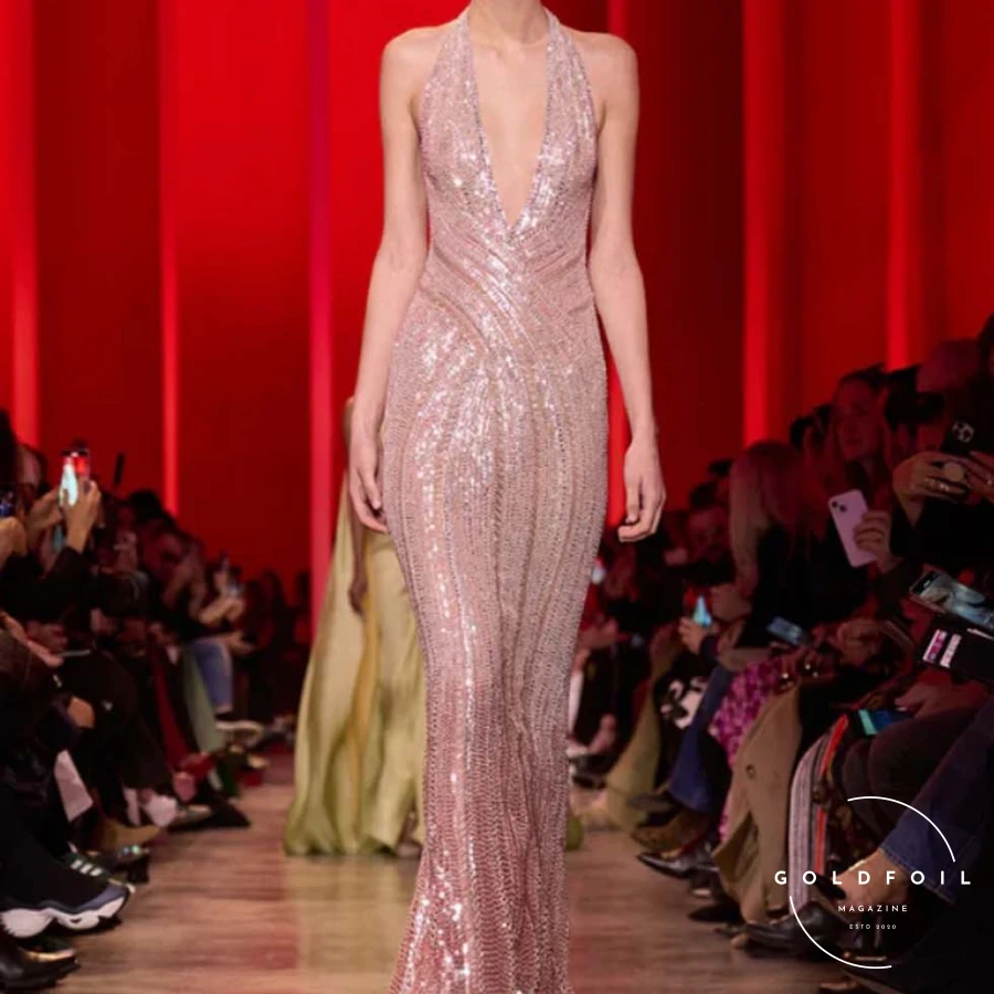 The show progressed from pitch-black to deep ruby and emerald tones, presenting sleek, sinuous shapes with sparse embroidery and tone-on-tone feathers and flower appliqués. As if emerging from darkness, gowns shimmered with moonlight-silver sequins, growing more sumptuous and voluminous. Rich embroidery and crystal beading adorned sensual see-through chiffon and organza, culminating in a lavish finale. The bridal dress was a cloud-like creation in blush tulle, intricately embroidered with pale gold curlicues and a regal train fit for a royal wedding. The show progressed from pitch-black to deep ruby and emerald tones, presenting sleek, sinuous shapes with sparse embroidery and tone-on-tone feathers and flower appliqués. As if emerging from darkness, gowns shimmered with moonlight-silver sequins, growing more sumptuous and voluminous. Rich embroidery and crystal beading adorned sensual see-through chiffon and organza, culminating in a lavish finale. The bridal dress was a cloud-like creation in blush tulle, intricately embroidered with pale gold curlicues and a regal train fit for a royal wedding.