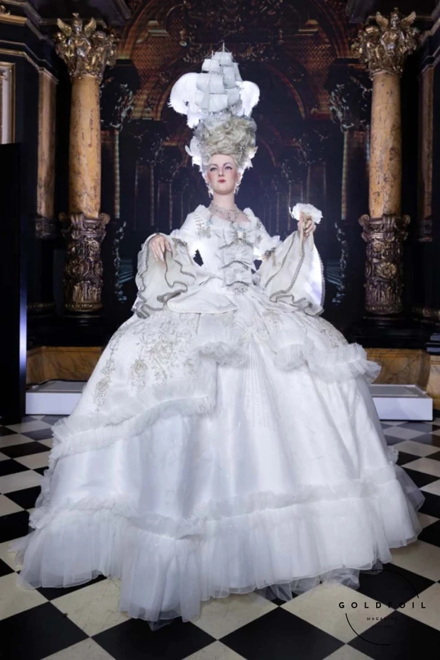 The highlight was the majestic court dress for Marie-Antoinette's statue, crafted from 1,500 meters of tulle and 120 meters of triple white silk organza, embroidered with symbols of the French court. The dress, light yet voluminous, featured intricate details like candlestick illuminations and 3D knots, embodying the timeless elegance and innovation that define both Fournié’s vision and haute couture itself. The highlight was the majestic court dress for Marie-Antoinette's statue, crafted from 1,500 meters of tulle and 120 meters of triple white silk organza, embroidered with symbols of the French court. The dress, light yet voluminous, featured intricate details like candlestick illuminations and 3D knots, embodying the timeless elegance and innovation that define both Fournié’s vision and haute couture itself.