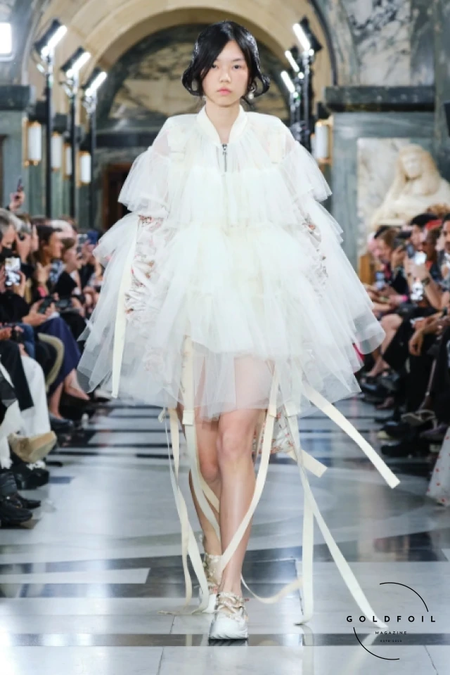 Simone Rocha is celebrated for her romantic and feminine designs that often feature delicate embellishments, intricate lace, and voluminous silhouettes. Her collections blend historical references with a contemporary sensibility. Simone Rocha is celebrated for her romantic and feminine designs that often feature delicate embellishments, intricate lace, and voluminous silhouettes. Her collections blend historical references with a contemporary sensibility.