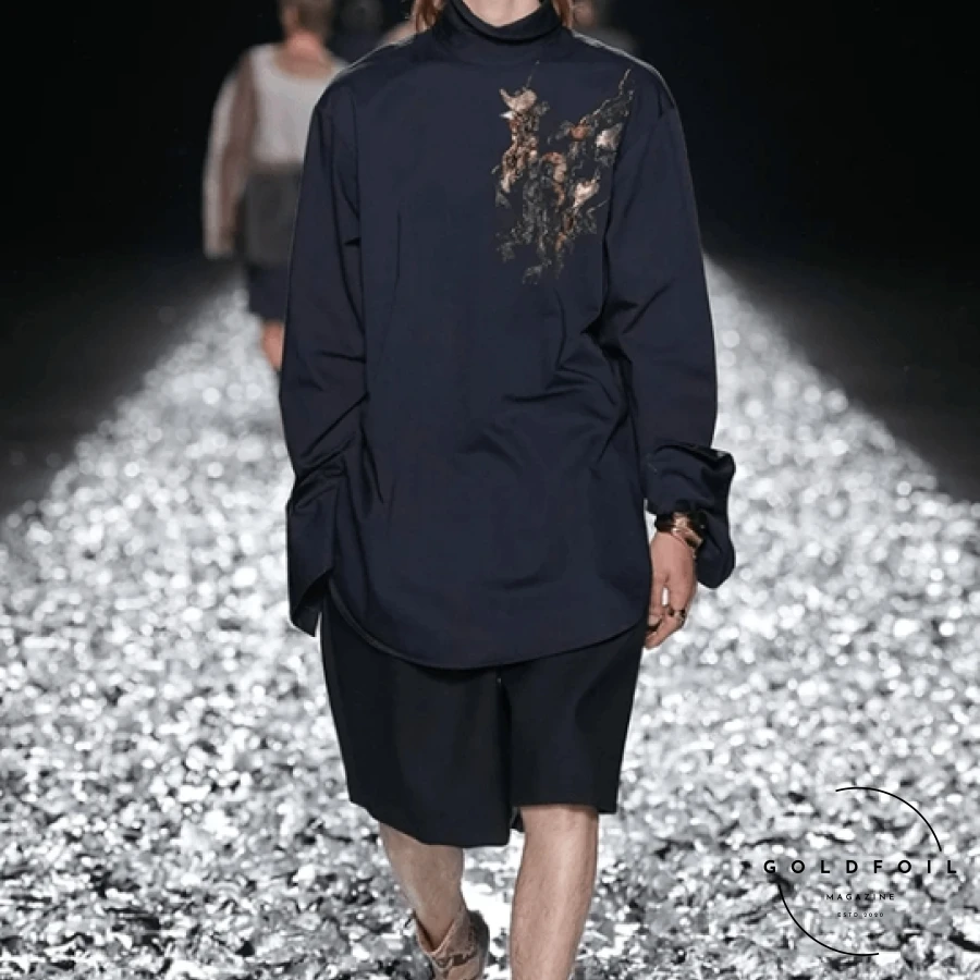 Dries Van Noten’s Spring/Summer 2025 collection marks the culmination of his illustrious career, a final tribute to his profound impact on menswear since 1986. Announced in March 2024, his retirement sets the stage for a masterful and reflective showcase. The runway, adorned with silver foil, mirrored the fluid silhouettes and organic flow of creativity that Van Noten is celebrated for. This final collection beautifully blends timeless and modern elements, embodying his design philosophy and cementing his legacy in fashion history. Dries Van Noten’s Spring/Summer 2025 collection marks the culmination of his illustrious career, a final tribute to his profound impact on menswear since 1986. Announced in March 2024, his retirement sets the stage for a masterful and reflective showcase. The runway, adorned with silver foil, mirrored the fluid silhouettes and organic flow of creativity that Van Noten is celebrated for. This final collection beautifully blends timeless and modern elements, embodying his design philosophy and cementing his legacy in fashion history.