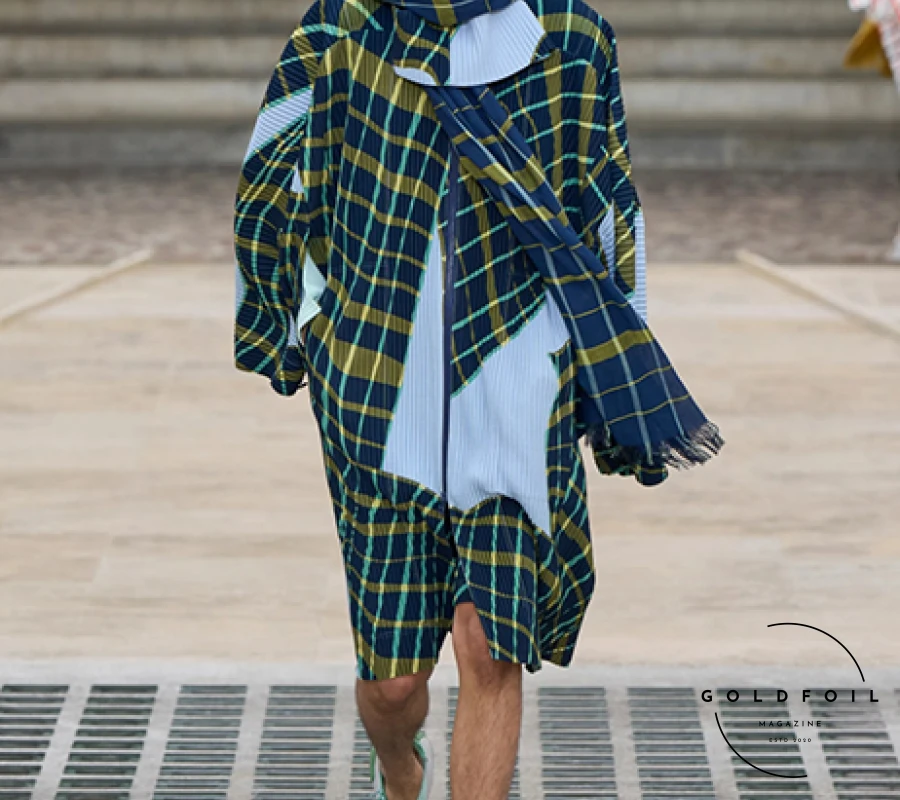 In the courtyard of the Mobilier National, Vincent de Belleval-designed slatted kites set the stage for Homme Plissé Issey Miyake's wind-inspired collection. The team took their theme seriously, reportedly even going on a parachute jump for research. Standout pieces included a pale ochre short-sleeved shirt, pant, and waistcoat with a matching tie, indicating a shift in tie trends. The collection featured dreamy wavy plaid patterns and garments with wing-like shoulders, while block-color pieces, inspired by kite construction, could be altered via buttons to sway in the breeze. In the courtyard of the Mobilier National, Vincent de Belleval-designed slatted kites set the stage for Homme Plissé Issey Miyake's wind-inspired collection. The team took their theme seriously, reportedly even going on a parachute jump for research. Standout pieces included a pale ochre short-sleeved shirt, pant, and waistcoat with a matching tie, indicating a shift in tie trends. The collection featured dreamy wavy plaid patterns and garments with wing-like shoulders, while block-color pieces, inspired by kite construction, could be altered via buttons to sway in the breeze.