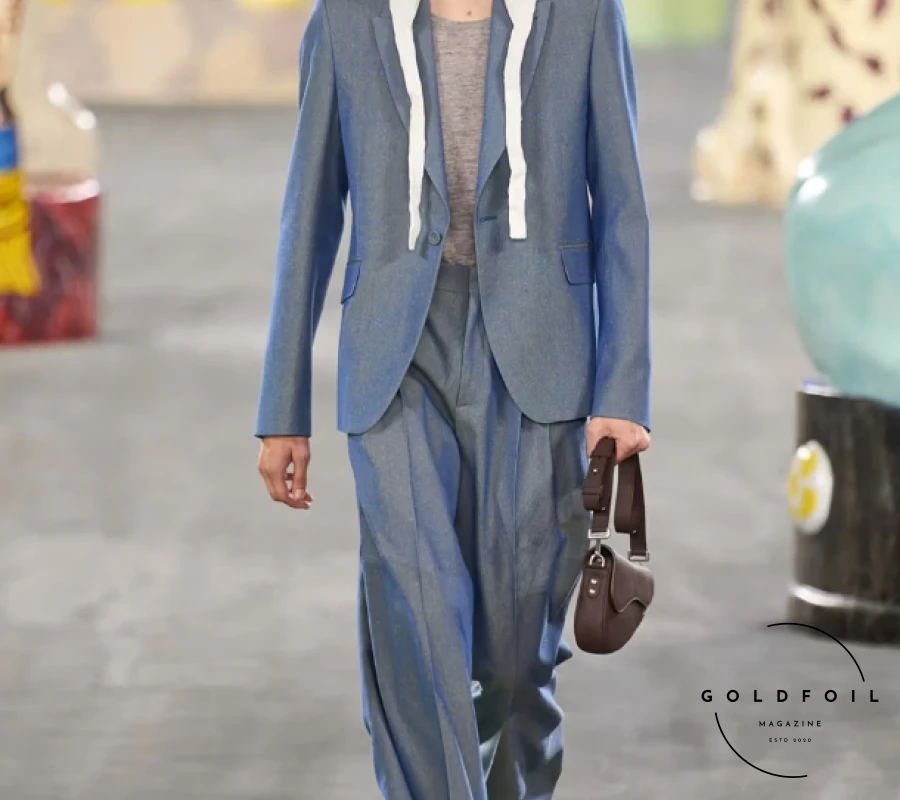 Kim Jones focused on craftsmanship and collaboration for Dior's SS25, emphasizing the skills of ateliers and artisans. Partnering with South African ceramicist Hylton Nel, Jones presented a collection celebrating work and personal expression, drawing parallels between Christian Dior, Nel, and himself. Nel's oversized cat statues adorned the runway alongside Jones' designs, which featured muted tones with vibrant accents like fluorescent vests and baby blue jackets. Nel's artwork also graced sweater vests and accessories, including a standout 70s-inspired drawstring collar, enriching the collection with artistic flair. Kim Jones focused on craftsmanship and collaboration for Dior's SS25, emphasizing the skills of ateliers and artisans. Partnering with South African ceramicist Hylton Nel, Jones presented a collection celebrating work and personal expression, drawing parallels between Christian Dior, Nel, and himself. Nel's oversized cat statues adorned the runway alongside Jones' designs, which featured muted tones with vibrant accents like fluorescent vests and baby blue jackets. Nel's artwork also graced sweater vests and accessories, including a standout 70s-inspired drawstring collar, enriching the collection with artistic flair.