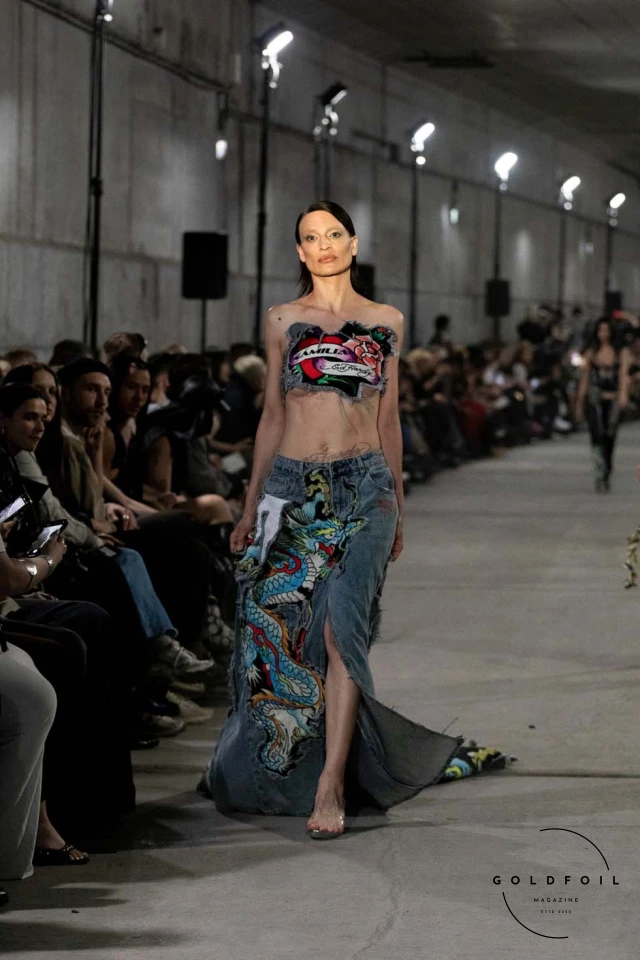 Namilia’s Spring/Summer 2025 runway show at Berlin Fashion Week was a visionary spectacle that fused futuristic design with potent social commentary. Designers Nan Li and Emilia Pfohl showcased a collection featuring high-tech fabrics, bold silhouettes, and symbolic embellishments depicting feminist icons. The use of biodegradable plastics, LED-embedded fabrics, and 3D-printed accessories highlighted the brand's commitment to sustainability, while oversized visors, holographic boots, and avant-garde jewellery added to the futuristic aesthetic. Multimedia presentations on gender equality, body positivity, and climate change underscored the show’s activist message, earning critical acclaim and reinforcing Namilia’s reputation for pushing fashion’s boundaries and inspiring change. Namilia’s Spring/Summer 2025 runway show at Berlin Fashion Week was a visionary spectacle that fused futuristic design with potent social commentary. Designers Nan Li and Emilia Pfohl showcased a collection featuring high-tech fabrics, bold silhouettes, and symbolic embellishments depicting feminist icons. The use of biodegradable plastics, LED-embedded fabrics, and 3D-printed accessories highlighted the brand's commitment to sustainability, while oversized visors, holographic boots, and avant-garde jewellery added to the futuristic aesthetic. Multimedia presentations on gender equality, body positivity, and climate change underscored the show’s activist message, earning critical acclaim and reinforcing Namilia’s reputation for pushing fashion’s boundaries and inspiring change.