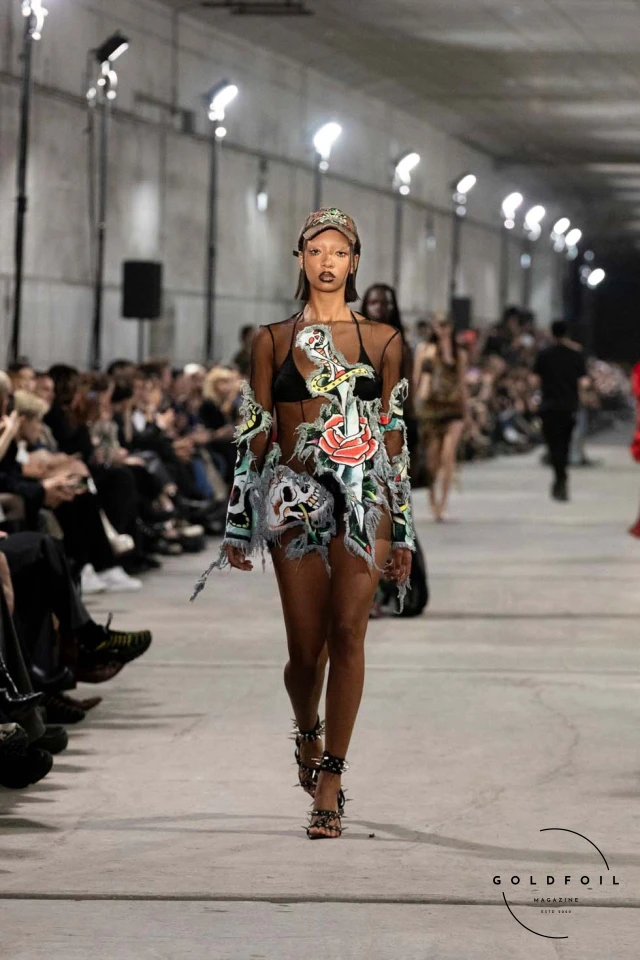 Namilia’s Spring/Summer 2025 runway show at Berlin Fashion Week was a visionary spectacle that fused futuristic design with potent social commentary. Designers Nan Li and Emilia Pfohl showcased a collection featuring high-tech fabrics, bold silhouettes, and symbolic embellishments depicting feminist icons. The use of biodegradable plastics, LED-embedded fabrics, and 3D-printed accessories highlighted the brand's commitment to sustainability, while oversized visors, holographic boots, and avant-garde jewellery added to the futuristic aesthetic. Multimedia presentations on gender equality, body positivity, and climate change underscored the show’s activist message, earning critical acclaim and reinforcing Namilia’s reputation for pushing fashion’s boundaries and inspiring change. Namilia’s Spring/Summer 2025 runway show at Berlin Fashion Week was a visionary spectacle that fused futuristic design with potent social commentary. Designers Nan Li and Emilia Pfohl showcased a collection featuring high-tech fabrics, bold silhouettes, and symbolic embellishments depicting feminist icons. The use of biodegradable plastics, LED-embedded fabrics, and 3D-printed accessories highlighted the brand's commitment to sustainability, while oversized visors, holographic boots, and avant-garde jewellery added to the futuristic aesthetic. Multimedia presentations on gender equality, body positivity, and climate change underscored the show’s activist message, earning critical acclaim and reinforcing Namilia’s reputation for pushing fashion’s boundaries and inspiring change.