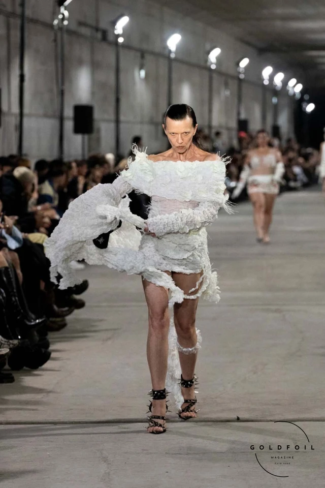 Namilia’s Spring/Summer 2025 runway show at Berlin Fashion Week was a visionary spectacle that fused futuristic design with potent social commentary. Designers Nan Li and Emilia Pfohl showcased a collection featuring high-tech fabrics, bold silhouettes, and symbolic embellishments depicting feminist icons. The use of biodegradable plastics, LED-embedded fabrics, and 3D-printed accessories highlighted the brand's commitment to sustainability, while oversized visors, holographic boots, and avant-garde jewellery added to the futuristic aesthetic. Multimedia presentations on gender equality, body positivity, and climate change underscored the show’s activist message, earning critical acclaim and reinforcing Namilia’s reputation for pushing fashion’s boundaries and inspiring change. Namilia’s Spring/Summer 2025 runway show at Berlin Fashion Week was a visionary spectacle that fused futuristic design with potent social commentary. Designers Nan Li and Emilia Pfohl showcased a collection featuring high-tech fabrics, bold silhouettes, and symbolic embellishments depicting feminist icons. The use of biodegradable plastics, LED-embedded fabrics, and 3D-printed accessories highlighted the brand's commitment to sustainability, while oversized visors, holographic boots, and avant-garde jewellery added to the futuristic aesthetic. Multimedia presentations on gender equality, body positivity, and climate change underscored the show’s activist message, earning critical acclaim and reinforcing Namilia’s reputation for pushing fashion’s boundaries and inspiring change.