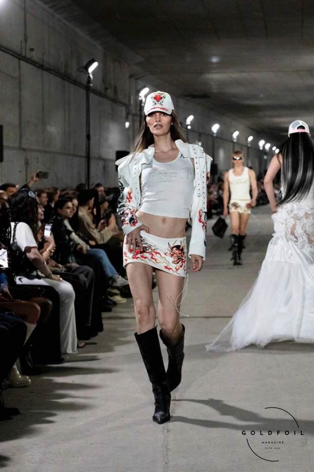 Namilia’s Spring/Summer 2025 runway show at Berlin Fashion Week was a visionary spectacle that fused futuristic design with potent social commentary. Designers Nan Li and Emilia Pfohl showcased a collection featuring high-tech fabrics, bold silhouettes, and symbolic embellishments depicting feminist icons. The use of biodegradable plastics, LED-embedded fabrics, and 3D-printed accessories highlighted the brand's commitment to sustainability, while oversized visors, holographic boots, and avant-garde jewellery added to the futuristic aesthetic. Multimedia presentations on gender equality, body positivity, and climate change underscored the show’s activist message, earning critical acclaim and reinforcing Namilia’s reputation for pushing fashion’s boundaries and inspiring change. Namilia’s Spring/Summer 2025 runway show at Berlin Fashion Week was a visionary spectacle that fused futuristic design with potent social commentary. Designers Nan Li and Emilia Pfohl showcased a collection featuring high-tech fabrics, bold silhouettes, and symbolic embellishments depicting feminist icons. The use of biodegradable plastics, LED-embedded fabrics, and 3D-printed accessories highlighted the brand's commitment to sustainability, while oversized visors, holographic boots, and avant-garde jewellery added to the futuristic aesthetic. Multimedia presentations on gender equality, body positivity, and climate change underscored the show’s activist message, earning critical acclaim and reinforcing Namilia’s reputation for pushing fashion’s boundaries and inspiring change.