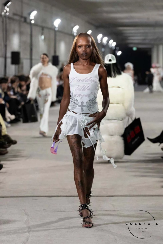 Namilia’s Spring/Summer 2025 runway show at Berlin Fashion Week was a visionary spectacle that fused futuristic design with potent social commentary. Designers Nan Li and Emilia Pfohl showcased a collection featuring high-tech fabrics, bold silhouettes, and symbolic embellishments depicting feminist icons. The use of biodegradable plastics, LED-embedded fabrics, and 3D-printed accessories highlighted the brand's commitment to sustainability, while oversized visors, holographic boots, and avant-garde jewellery added to the futuristic aesthetic. Multimedia presentations on gender equality, body positivity, and climate change underscored the show’s activist message, earning critical acclaim and reinforcing Namilia’s reputation for pushing fashion’s boundaries and inspiring change. Namilia’s Spring/Summer 2025 runway show at Berlin Fashion Week was a visionary spectacle that fused futuristic design with potent social commentary. Designers Nan Li and Emilia Pfohl showcased a collection featuring high-tech fabrics, bold silhouettes, and symbolic embellishments depicting feminist icons. The use of biodegradable plastics, LED-embedded fabrics, and 3D-printed accessories highlighted the brand's commitment to sustainability, while oversized visors, holographic boots, and avant-garde jewellery added to the futuristic aesthetic. Multimedia presentations on gender equality, body positivity, and climate change underscored the show’s activist message, earning critical acclaim and reinforcing Namilia’s reputation for pushing fashion’s boundaries and inspiring change.