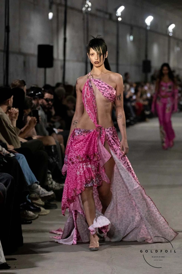 Namilia’s Spring/Summer 2025 runway show at Berlin Fashion Week was a visionary spectacle that fused futuristic design with potent social commentary. Designers Nan Li and Emilia Pfohl showcased a collection featuring high-tech fabrics, bold silhouettes, and symbolic embellishments depicting feminist icons. The use of biodegradable plastics, LED-embedded fabrics, and 3D-printed accessories highlighted the brand's commitment to sustainability, while oversized visors, holographic boots, and avant-garde jewellery added to the futuristic aesthetic. Multimedia presentations on gender equality, body positivity, and climate change underscored the show’s activist message, earning critical acclaim and reinforcing Namilia’s reputation for pushing fashion’s boundaries and inspiring change. Namilia’s Spring/Summer 2025 runway show at Berlin Fashion Week was a visionary spectacle that fused futuristic design with potent social commentary. Designers Nan Li and Emilia Pfohl showcased a collection featuring high-tech fabrics, bold silhouettes, and symbolic embellishments depicting feminist icons. The use of biodegradable plastics, LED-embedded fabrics, and 3D-printed accessories highlighted the brand's commitment to sustainability, while oversized visors, holographic boots, and avant-garde jewellery added to the futuristic aesthetic. Multimedia presentations on gender equality, body positivity, and climate change underscored the show’s activist message, earning critical acclaim and reinforcing Namilia’s reputation for pushing fashion’s boundaries and inspiring change.