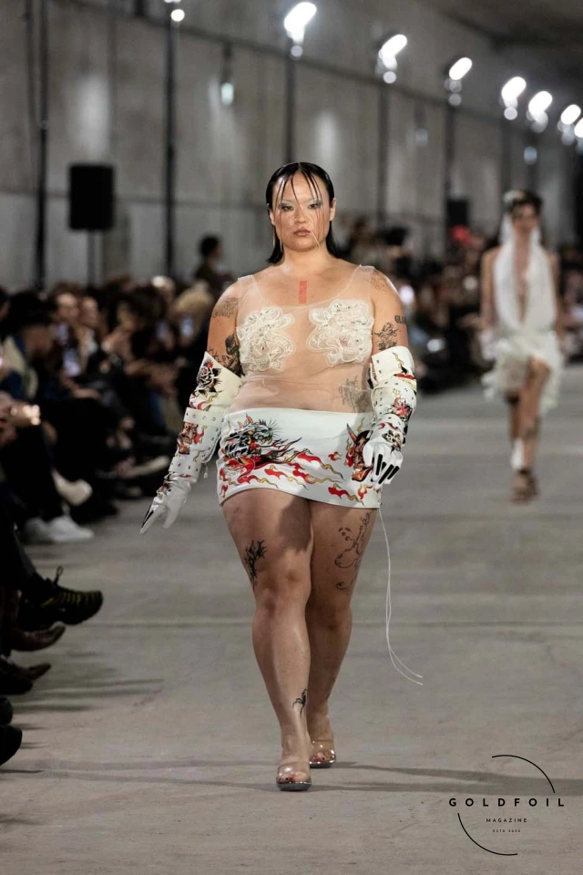 Namilia’s Spring/Summer 2025 runway show at Berlin Fashion Week was a visionary spectacle that fused futuristic design with potent social commentary. Designers Nan Li and Emilia Pfohl showcased a collection featuring high-tech fabrics, bold silhouettes, and symbolic embellishments depicting feminist icons. The use of biodegradable plastics, LED-embedded fabrics, and 3D-printed accessories highlighted the brand's commitment to sustainability, while oversized visors, holographic boots, and avant-garde jewellery added to the futuristic aesthetic. Multimedia presentations on gender equality, body positivity, and climate change underscored the show’s activist message, earning critical acclaim and reinforcing Namilia’s reputation for pushing fashion’s boundaries and inspiring change. Namilia’s Spring/Summer 2025 runway show at Berlin Fashion Week was a visionary spectacle that fused futuristic design with potent social commentary. Designers Nan Li and Emilia Pfohl showcased a collection featuring high-tech fabrics, bold silhouettes, and symbolic embellishments depicting feminist icons. The use of biodegradable plastics, LED-embedded fabrics, and 3D-printed accessories highlighted the brand's commitment to sustainability, while oversized visors, holographic boots, and avant-garde jewellery added to the futuristic aesthetic. Multimedia presentations on gender equality, body positivity, and climate change underscored the show’s activist message, earning critical acclaim and reinforcing Namilia’s reputation for pushing fashion’s boundaries and inspiring change.