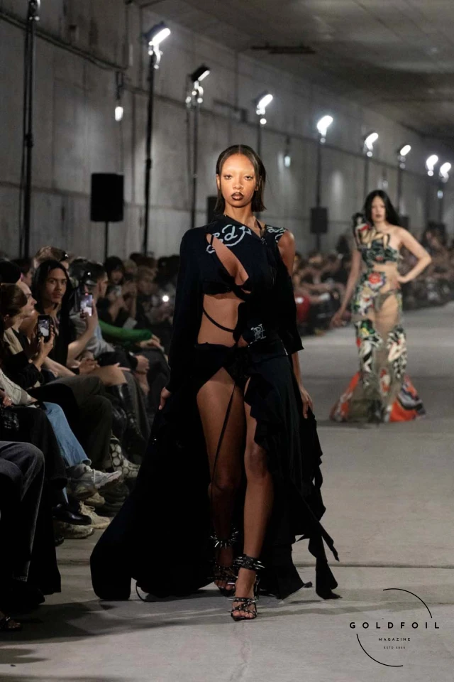 Namilia’s Spring/Summer 2025 runway show at Berlin Fashion Week was a visionary spectacle that fused futuristic design with potent social commentary. Designers Nan Li and Emilia Pfohl showcased a collection featuring high-tech fabrics, bold silhouettes, and symbolic embellishments depicting feminist icons. The use of biodegradable plastics, LED-embedded fabrics, and 3D-printed accessories highlighted the brand's commitment to sustainability, while oversized visors, holographic boots, and avant-garde jewellery added to the futuristic aesthetic. Multimedia presentations on gender equality, body positivity, and climate change underscored the show’s activist message, earning critical acclaim and reinforcing Namilia’s reputation for pushing fashion’s boundaries and inspiring change. Namilia’s Spring/Summer 2025 runway show at Berlin Fashion Week was a visionary spectacle that fused futuristic design with potent social commentary. Designers Nan Li and Emilia Pfohl showcased a collection featuring high-tech fabrics, bold silhouettes, and symbolic embellishments depicting feminist icons. The use of biodegradable plastics, LED-embedded fabrics, and 3D-printed accessories highlighted the brand's commitment to sustainability, while oversized visors, holographic boots, and avant-garde jewellery added to the futuristic aesthetic. Multimedia presentations on gender equality, body positivity, and climate change underscored the show’s activist message, earning critical acclaim and reinforcing Namilia’s reputation for pushing fashion’s boundaries and inspiring change.