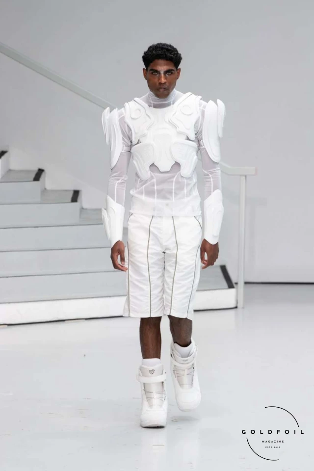 Yenesai’s latest collection, inspired by the desert biome, offers innovative solutions and challenges through color theory, soft fabrics, refined basics, and explorative accessories tailored for the future nomad. Emphasizing functionality, the collection includes garments that facilitate movement and action, while incorporating harvested resources like crystals and essential oils in their new clear resin canister bag. Advances in 3D-printed accessories, including a cyborg hand clasp and redesigned eyewear, reflect the nomad’s evolving relationship with the environment, showcased in shiny, flecked fabrics and gemstone-inspired textures. The show concludes with leather looks featuring intricate paneling and armor-style layering. Yenesai, named after the Yenesai River, blends futuristic vision with ancestral nomadic values, offering technical fabrics and striking silhouettes for a global community of travelers, and fostering creative collaboration through retreats and events. Yenesai’s latest collection, inspired by the desert biome, offers innovative solutions and challenges through color theory, soft fabrics, refined basics, and explorative accessories tailored for the future nomad. Emphasizing functionality, the collection includes garments that facilitate movement and action, while incorporating harvested resources like crystals and essential oils in their new clear resin canister bag. Advances in 3D-printed accessories, including a cyborg hand clasp and redesigned eyewear, reflect the nomad’s evolving relationship with the environment, showcased in shiny, flecked fabrics and gemstone-inspired textures. The show concludes with leather looks featuring intricate paneling and armor-style layering. Yenesai, named after the Yenesai River, blends futuristic vision with ancestral nomadic values, offering technical fabrics and striking silhouettes for a global community of travelers, and fostering creative collaboration through retreats and events.
