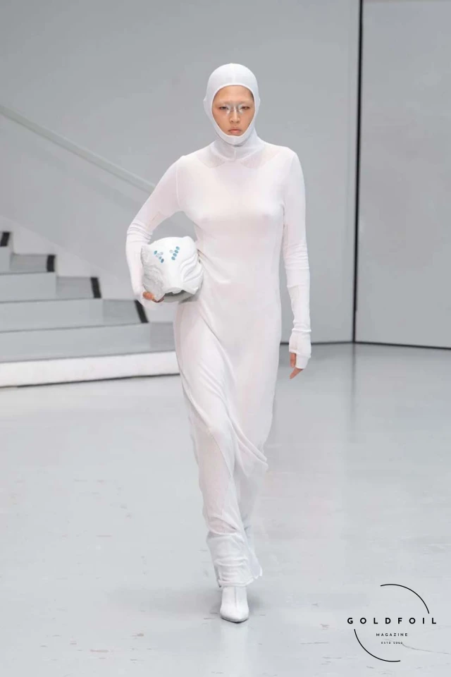 Yenesai’s latest collection, inspired by the desert biome, offers innovative solutions and challenges through color theory, soft fabrics, refined basics, and explorative accessories tailored for the future nomad. Emphasizing functionality, the collection includes garments that facilitate movement and action, while incorporating harvested resources like crystals and essential oils in their new clear resin canister bag. Advances in 3D-printed accessories, including a cyborg hand clasp and redesigned eyewear, reflect the nomad’s evolving relationship with the environment, showcased in shiny, flecked fabrics and gemstone-inspired textures. The show concludes with leather looks featuring intricate paneling and armor-style layering. Yenesai, named after the Yenesai River, blends futuristic vision with ancestral nomadic values, offering technical fabrics and striking silhouettes for a global community of travelers, and fostering creative collaboration through retreats and events. Yenesai’s latest collection, inspired by the desert biome, offers innovative solutions and challenges through color theory, soft fabrics, refined basics, and explorative accessories tailored for the future nomad. Emphasizing functionality, the collection includes garments that facilitate movement and action, while incorporating harvested resources like crystals and essential oils in their new clear resin canister bag. Advances in 3D-printed accessories, including a cyborg hand clasp and redesigned eyewear, reflect the nomad’s evolving relationship with the environment, showcased in shiny, flecked fabrics and gemstone-inspired textures. The show concludes with leather looks featuring intricate paneling and armor-style layering. Yenesai, named after the Yenesai River, blends futuristic vision with ancestral nomadic values, offering technical fabrics and striking silhouettes for a global community of travelers, and fostering creative collaboration through retreats and events.