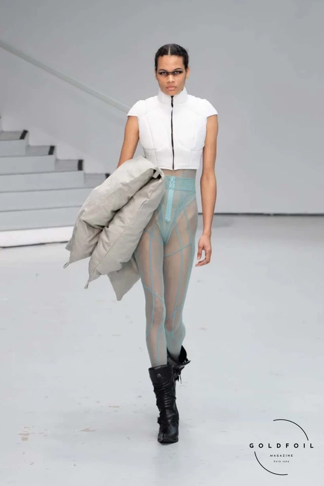 Yenesai’s latest collection, inspired by the desert biome, offers innovative solutions and challenges through color theory, soft fabrics, refined basics, and explorative accessories tailored for the future nomad. Emphasizing functionality, the collection includes garments that facilitate movement and action, while incorporating harvested resources like crystals and essential oils in their new clear resin canister bag. Advances in 3D-printed accessories, including a cyborg hand clasp and redesigned eyewear, reflect the nomad’s evolving relationship with the environment, showcased in shiny, flecked fabrics and gemstone-inspired textures. The show concludes with leather looks featuring intricate paneling and armor-style layering. Yenesai, named after the Yenesai River, blends futuristic vision with ancestral nomadic values, offering technical fabrics and striking silhouettes for a global community of travelers, and fostering creative collaboration through retreats and events. Yenesai’s latest collection, inspired by the desert biome, offers innovative solutions and challenges through color theory, soft fabrics, refined basics, and explorative accessories tailored for the future nomad. Emphasizing functionality, the collection includes garments that facilitate movement and action, while incorporating harvested resources like crystals and essential oils in their new clear resin canister bag. Advances in 3D-printed accessories, including a cyborg hand clasp and redesigned eyewear, reflect the nomad’s evolving relationship with the environment, showcased in shiny, flecked fabrics and gemstone-inspired textures. The show concludes with leather looks featuring intricate paneling and armor-style layering. Yenesai, named after the Yenesai River, blends futuristic vision with ancestral nomadic values, offering technical fabrics and striking silhouettes for a global community of travelers, and fostering creative collaboration through retreats and events.