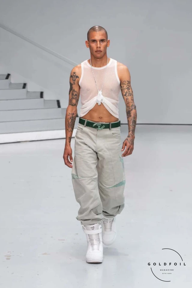 Yenesai’s latest collection, inspired by the desert biome, offers innovative solutions and challenges through color theory, soft fabrics, refined basics, and explorative accessories tailored for the future nomad. Emphasizing functionality, the collection includes garments that facilitate movement and action, while incorporating harvested resources like crystals and essential oils in their new clear resin canister bag. Advances in 3D-printed accessories, including a cyborg hand clasp and redesigned eyewear, reflect the nomad’s evolving relationship with the environment, showcased in shiny, flecked fabrics and gemstone-inspired textures. The show concludes with leather looks featuring intricate paneling and armor-style layering. Yenesai, named after the Yenesai River, blends futuristic vision with ancestral nomadic values, offering technical fabrics and striking silhouettes for a global community of travelers, and fostering creative collaboration through retreats and events. Yenesai’s latest collection, inspired by the desert biome, offers innovative solutions and challenges through color theory, soft fabrics, refined basics, and explorative accessories tailored for the future nomad. Emphasizing functionality, the collection includes garments that facilitate movement and action, while incorporating harvested resources like crystals and essential oils in their new clear resin canister bag. Advances in 3D-printed accessories, including a cyborg hand clasp and redesigned eyewear, reflect the nomad’s evolving relationship with the environment, showcased in shiny, flecked fabrics and gemstone-inspired textures. The show concludes with leather looks featuring intricate paneling and armor-style layering. Yenesai, named after the Yenesai River, blends futuristic vision with ancestral nomadic values, offering technical fabrics and striking silhouettes for a global community of travelers, and fostering creative collaboration through retreats and events.