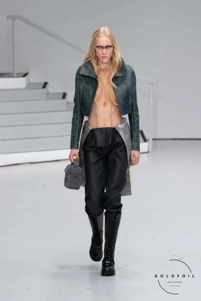 Yenesai’s latest collection, inspired by the desert biome, offers innovative solutions and challenges through color theory, soft fabrics, refined basics, and explorative accessories tailored for the future nomad. Emphasizing functionality, the collection includes garments that facilitate movement and action, while incorporating harvested resources like crystals and essential oils in their new clear resin canister bag. Advances in 3D-printed accessories, including a cyborg hand clasp and redesigned eyewear, reflect the nomad’s evolving relationship with the environment, showcased in shiny, flecked fabrics and gemstone-inspired textures. The show concludes with leather looks featuring intricate paneling and armor-style layering. Yenesai, named after the Yenesai River, blends futuristic vision with ancestral nomadic values, offering technical fabrics and striking silhouettes for a global community of travelers, and fostering creative collaboration through retreats and events. Yenesai’s latest collection, inspired by the desert biome, offers innovative solutions and challenges through color theory, soft fabrics, refined basics, and explorative accessories tailored for the future nomad. Emphasizing functionality, the collection includes garments that facilitate movement and action, while incorporating harvested resources like crystals and essential oils in their new clear resin canister bag. Advances in 3D-printed accessories, including a cyborg hand clasp and redesigned eyewear, reflect the nomad’s evolving relationship with the environment, showcased in shiny, flecked fabrics and gemstone-inspired textures. The show concludes with leather looks featuring intricate paneling and armor-style layering. Yenesai, named after the Yenesai River, blends futuristic vision with ancestral nomadic values, offering technical fabrics and striking silhouettes for a global community of travelers, and fostering creative collaboration through retreats and events.