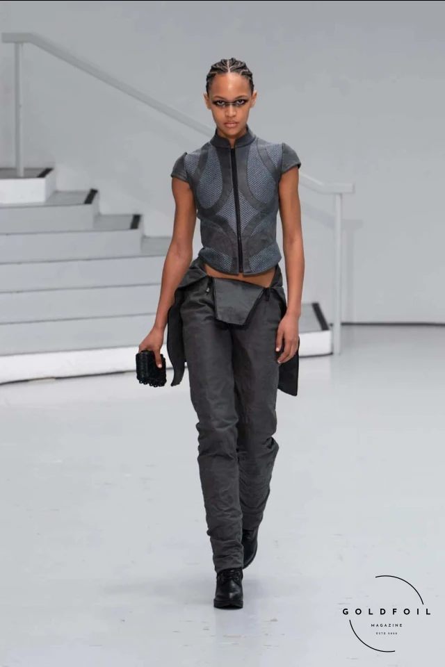 Yenesai’s latest collection, inspired by the desert biome, offers innovative solutions and challenges through color theory, soft fabrics, refined basics, and explorative accessories tailored for the future nomad. Emphasizing functionality, the collection includes garments that facilitate movement and action, while incorporating harvested resources like crystals and essential oils in their new clear resin canister bag. Advances in 3D-printed accessories, including a cyborg hand clasp and redesigned eyewear, reflect the nomad’s evolving relationship with the environment, showcased in shiny, flecked fabrics and gemstone-inspired textures. The show concludes with leather looks featuring intricate paneling and armor-style layering. Yenesai, named after the Yenesai River, blends futuristic vision with ancestral nomadic values, offering technical fabrics and striking silhouettes for a global community of travelers, and fostering creative collaboration through retreats and events. Yenesai’s latest collection, inspired by the desert biome, offers innovative solutions and challenges through color theory, soft fabrics, refined basics, and explorative accessories tailored for the future nomad. Emphasizing functionality, the collection includes garments that facilitate movement and action, while incorporating harvested resources like crystals and essential oils in their new clear resin canister bag. Advances in 3D-printed accessories, including a cyborg hand clasp and redesigned eyewear, reflect the nomad’s evolving relationship with the environment, showcased in shiny, flecked fabrics and gemstone-inspired textures. The show concludes with leather looks featuring intricate paneling and armor-style layering. Yenesai, named after the Yenesai River, blends futuristic vision with ancestral nomadic values, offering technical fabrics and striking silhouettes for a global community of travelers, and fostering creative collaboration through retreats and events.