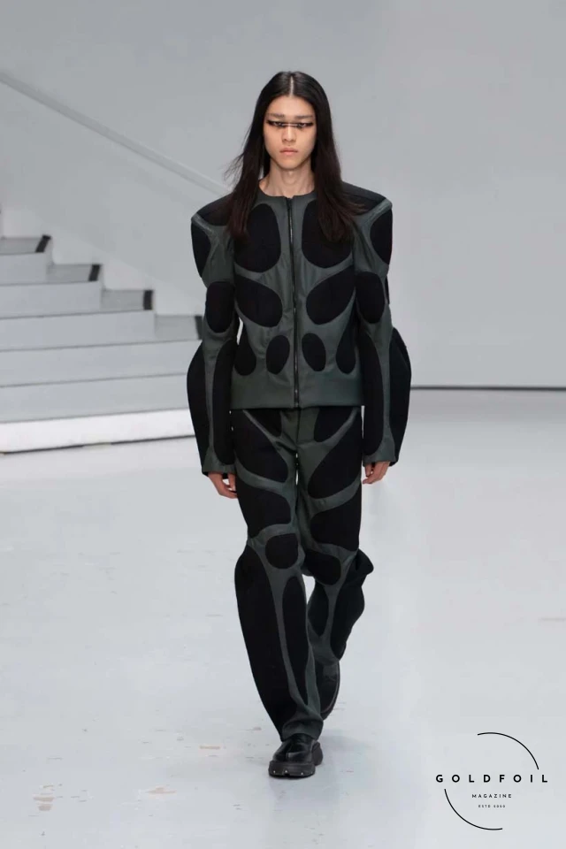 Yenesai’s latest collection, inspired by the desert biome, offers innovative solutions and challenges through color theory, soft fabrics, refined basics, and explorative accessories tailored for the future nomad. Emphasizing functionality, the collection includes garments that facilitate movement and action, while incorporating harvested resources like crystals and essential oils in their new clear resin canister bag. Advances in 3D-printed accessories, including a cyborg hand clasp and redesigned eyewear, reflect the nomad’s evolving relationship with the environment, showcased in shiny, flecked fabrics and gemstone-inspired textures. The show concludes with leather looks featuring intricate paneling and armor-style layering. Yenesai, named after the Yenesai River, blends futuristic vision with ancestral nomadic values, offering technical fabrics and striking silhouettes for a global community of travelers, and fostering creative collaboration through retreats and events. Yenesai’s latest collection, inspired by the desert biome, offers innovative solutions and challenges through color theory, soft fabrics, refined basics, and explorative accessories tailored for the future nomad. Emphasizing functionality, the collection includes garments that facilitate movement and action, while incorporating harvested resources like crystals and essential oils in their new clear resin canister bag. Advances in 3D-printed accessories, including a cyborg hand clasp and redesigned eyewear, reflect the nomad’s evolving relationship with the environment, showcased in shiny, flecked fabrics and gemstone-inspired textures. The show concludes with leather looks featuring intricate paneling and armor-style layering. Yenesai, named after the Yenesai River, blends futuristic vision with ancestral nomadic values, offering technical fabrics and striking silhouettes for a global community of travelers, and fostering creative collaboration through retreats and events.