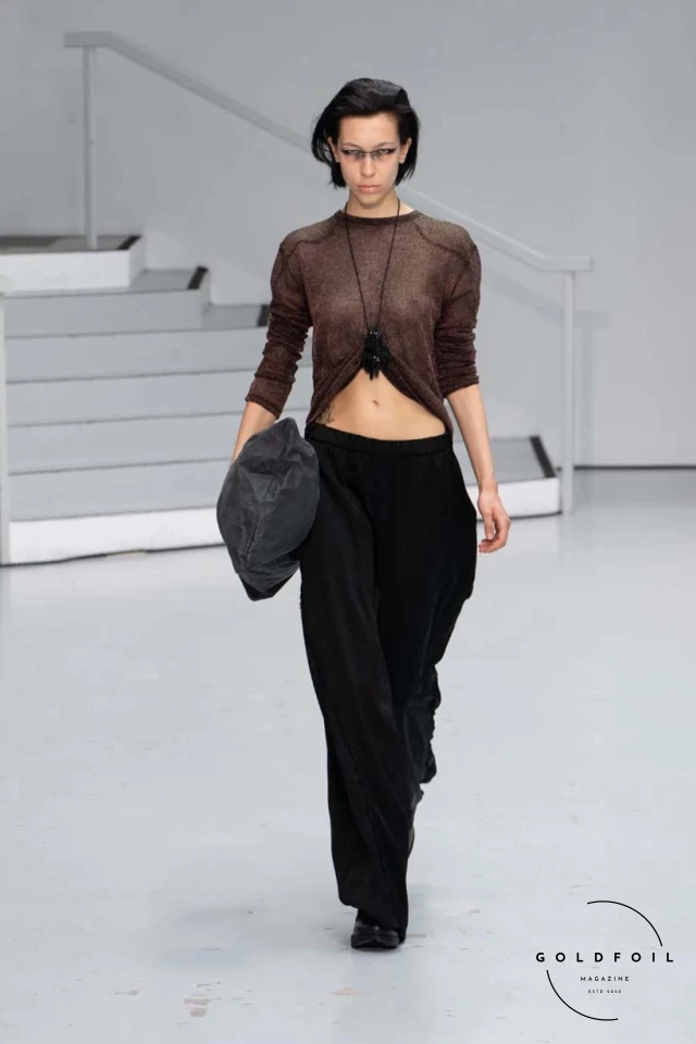 Yenesai’s latest collection, inspired by the desert biome, offers innovative solutions and challenges through color theory, soft fabrics, refined basics, and explorative accessories tailored for the future nomad. Emphasizing functionality, the collection includes garments that facilitate movement and action, while incorporating harvested resources like crystals and essential oils in their new clear resin canister bag. Advances in 3D-printed accessories, including a cyborg hand clasp and redesigned eyewear, reflect the nomad’s evolving relationship with the environment, showcased in shiny, flecked fabrics and gemstone-inspired textures. The show concludes with leather looks featuring intricate paneling and armor-style layering. Yenesai, named after the Yenesai River, blends futuristic vision with ancestral nomadic values, offering technical fabrics and striking silhouettes for a global community of travelers, and fostering creative collaboration through retreats and events. Yenesai’s latest collection, inspired by the desert biome, offers innovative solutions and challenges through color theory, soft fabrics, refined basics, and explorative accessories tailored for the future nomad. Emphasizing functionality, the collection includes garments that facilitate movement and action, while incorporating harvested resources like crystals and essential oils in their new clear resin canister bag. Advances in 3D-printed accessories, including a cyborg hand clasp and redesigned eyewear, reflect the nomad’s evolving relationship with the environment, showcased in shiny, flecked fabrics and gemstone-inspired textures. The show concludes with leather looks featuring intricate paneling and armor-style layering. Yenesai, named after the Yenesai River, blends futuristic vision with ancestral nomadic values, offering technical fabrics and striking silhouettes for a global community of travelers, and fostering creative collaboration through retreats and events.