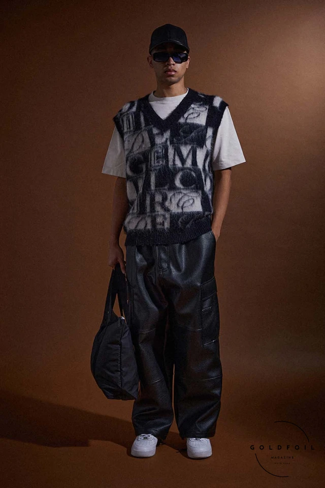 model wears a mohair vest in black and white typography with leather cargo pants, white trainers and a denim tote. Criminal Damage, London's iconic streetwear brand established in 1991, redefines the fashion landscape with its FW24  model wears a mohair vest in black and white typography with leather cargo pants, white trainers and a denim tote. Criminal Damage, London's iconic streetwear brand established in 1991, redefines the fashion landscape with its FW24